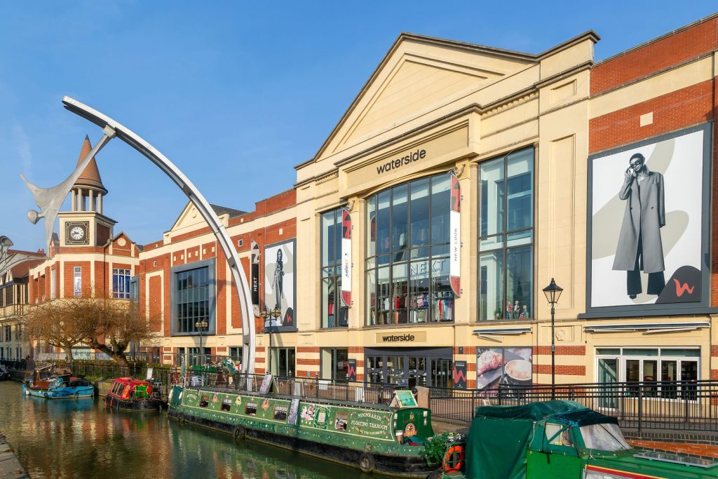 Narrow boats River Witham waterside shopping centre, Lincoln, Lincolnshire, England, UK - Millennium Empowerment Sculpture by Stephen Broadben